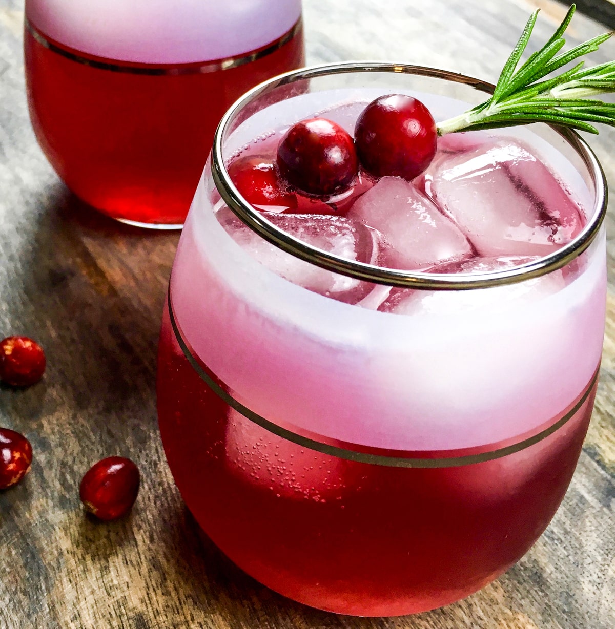 cinnamon cranberry spritzer holiday cocktail with rosemary garnish